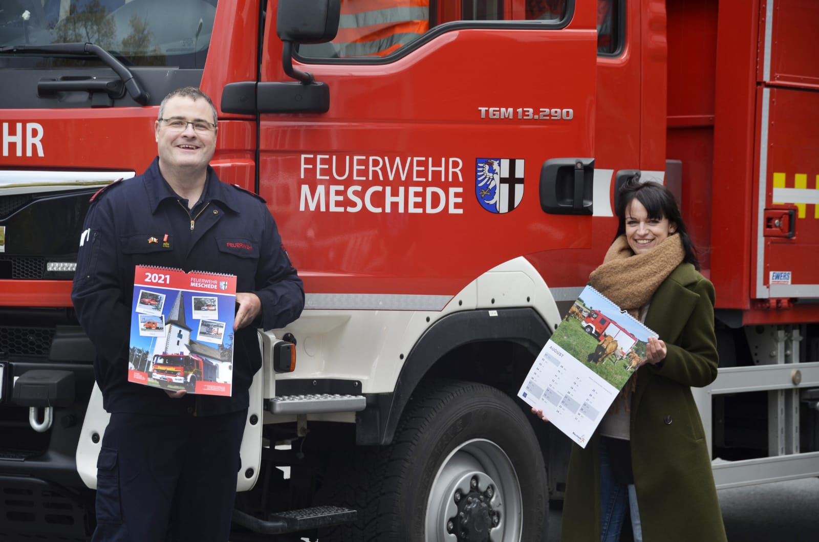 Hans-Jörg Steiner (Freiwillige Feuerwehr der Stadt Meschede) und Steffi Kroggel (Stadtmarketing Meschede) präsentieren den Feuerwehrkalender 2021. Bildnachweis: Stadtmarketing Meschede