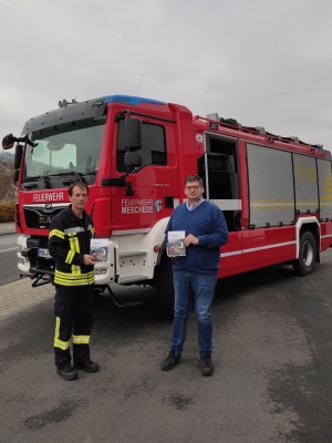 Das Bild zeigt den Autor Andre Streich (rechts im Bild) bei der Buchbergabe an den Pressesprecher Holger Peek